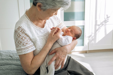 Grandmother admires her sweet granddaughter. Great-grandmother plays with a newborn...