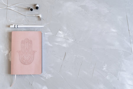 Flatlay with notepad, pen and headphones. Planning your business. Pink notebook on gray background.の写真素材