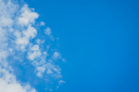Bright blue sky with white clouds. Place for text on a blue background
