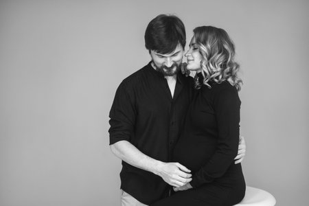 A happy man stands next to his pregnant girlfriend. loving parents are waiting for the birth of a baby. Husband hugs his pregnant wifes stomachの写真素材