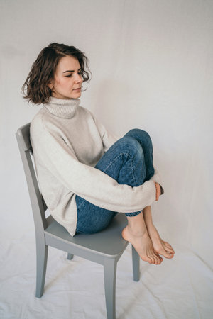 Vertical portrait of a beautiful brunette. A cozy photo of a girl in a gray sweater
