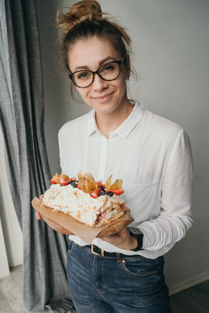 The pastry chef holds a meringue roll in his hands. The girl shows her pastries. Housewife holding a delicious dessert in her handsの写真素材