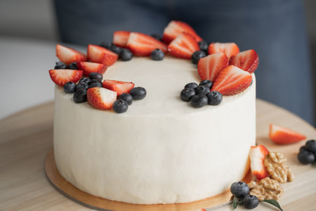 Homemade cake with cheese cream and fresh berries. The pastry chef decorates the cake with...