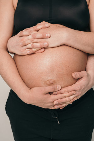 The belly of a pregnant girl is close-up. The husband is careful to hold the belly of the pregnant...