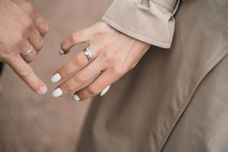 Newlyweds holding hands. Guy holding his girlfriend is hand. Wedding rings on his hands
