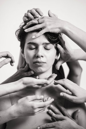 Black and white portrait of a beautiful girl. Lots of hands around a womans face. Creative portrait...