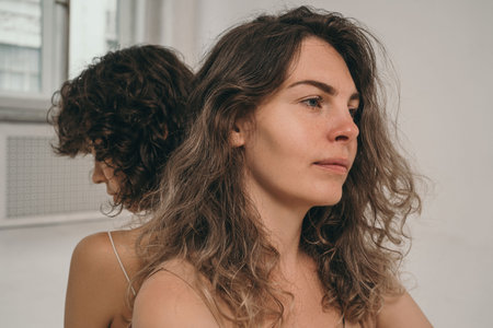 A beautiful girl with curly hair looks into the frame. A girl without makeup. A beautiful and...