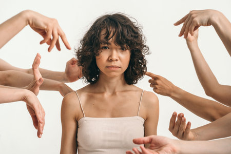 The impact of the environment on humans. A beautiful curly woman looks into the frame. Lots of hands near a beautiful girl. Introspection and self-study in a womanの写真素材