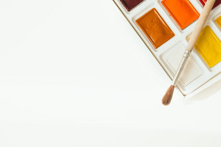 Bright watercolor paints on a white background. A place for text. The brush lies next to the paints. Multi-colored paints close-upの写真素材