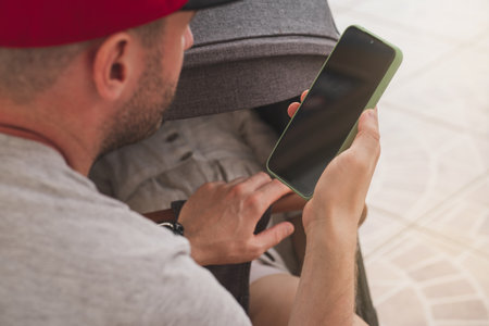 A young dad works remotely with the kids. Adults are always online and do not follow children. The father puts the child to bed in a strollerの写真素材