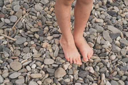 Prevention of flat feet in children. The child walks on the stones with his bare feet. Treatment of valgus foot in children and adults. Close-up of the childs foot on the rocksの写真素材