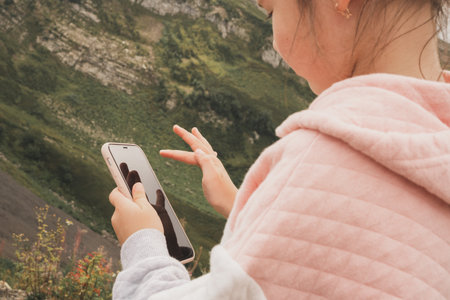 Childrens dependence on gadgets and games. The girl plays games on her smartphone. Digital education in childrenの写真素材