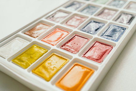 Bright watercolor paints on a white background. A place for text. The brush lies next to the paints. Multi-colored paints close-upの写真素材