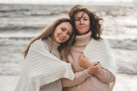 close friends support each other. the sisters walk together by the sea in the fall. the girls...