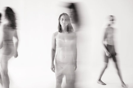 The girl got lost in the crowd. One person is clear, and the crowd is smeared. The girl confidently stands among the running peopleの写真素材