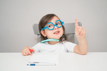 A small child in a doctors costume. An artistic girl plays doctor. A child in glasses and a white T-shirt.の写真素材