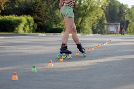 Roller skater woman in shorts training in the park, strong legs in motion