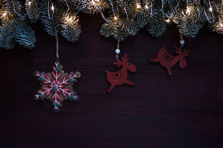 dark christmas background with garland lights and wooden snowflake and deers