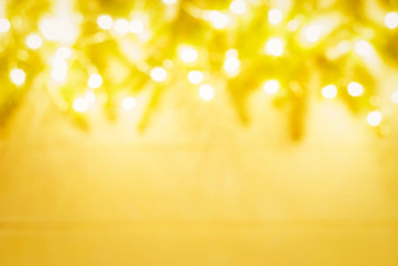 blurred christmas background with gold garland lights and spruce branches frameの写真素材