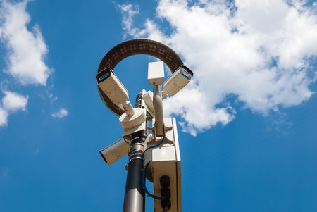 outdoor surveillance cameras on lamppost with led lantern against blue sky