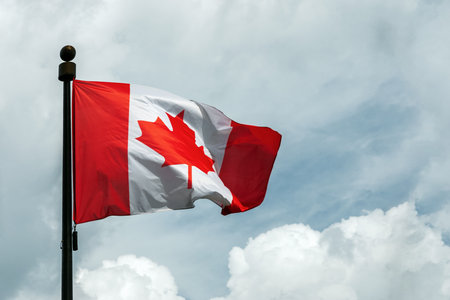 Flag of Canada on flagpole floating in the skyの写真素材