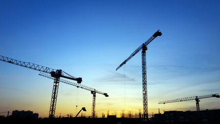 Construction crane silhouettes in blue sky at sunsetの写真素材