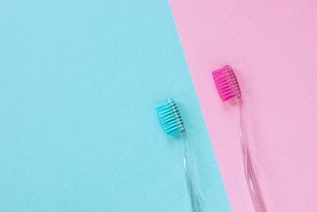Pink and blue toothbrushes for him and her, minimal design with copy space