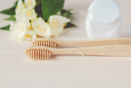 Two bamboo toothbrushes, dental floss and white flowers, closeupの写真素材