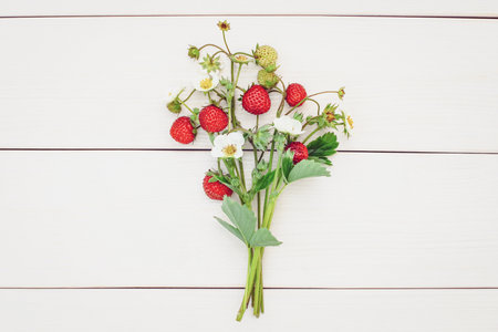 Bunch of strawberries with flowers, strawberry bouquet on white wooden backgroundの写真素材