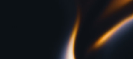 Golden flame on black grainy textured background, abstract blurred orange waves on dark noise texture, copy spaceの写真素材