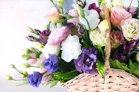 Beautiful multi-colored bouquet of flowers in a straw basket with a handle. White, pink, purple,...