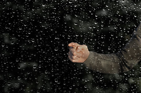 hand behind a wet windowの写真素材