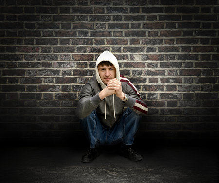 young man sits near a wall