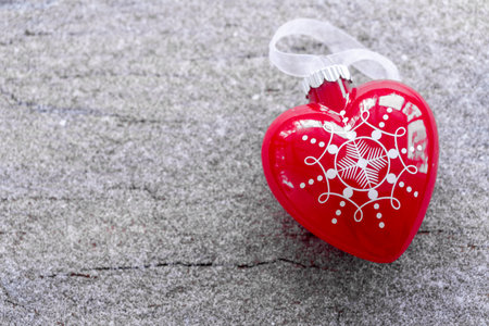 toy in the form of a heart, lying on a snow-covered wooden surface. Christmas toys