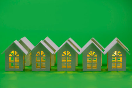 wooden house with lights on a green background.conceptual photoの写真素材