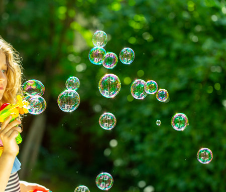 bubble. little girl blowing bubbles in the summer garden
