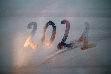 new year's numbers 2021 written on a fogged bathroom window in partial blur, close-up