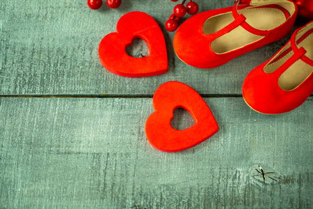 red baby shoes as decor and background on the dark wood surface, Christmas decorations for newborns close-upの写真素材