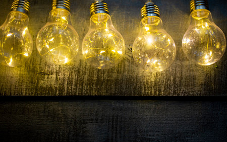 wooden background with a lighted light bulb in partial blur close-up