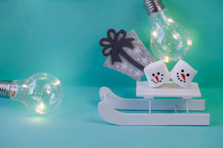marshmallow snowmen ride on a sled on a turquoise background in close-up Christmas decorations