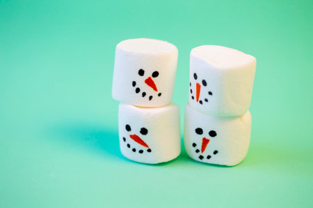 marshmallow snowmen ride on a sled on a turquoise background in close-up Christmas decorationsの写真素材