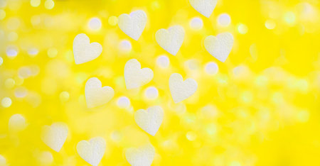 yellow background with bokeh of white foam hearts and light from a garland in partial blur, background of white heartsの写真素材