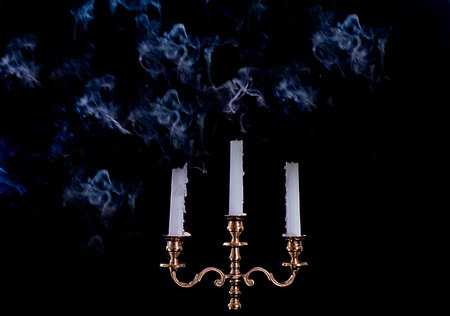 smoke from a burning candle in candelabra on a black background, close-upの写真素材