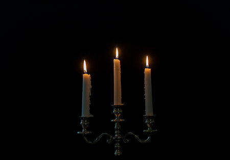 burning candles in candelabra on a black background, close-upの写真素材