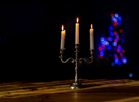 burning candles in candelabra with bright bokeh on a black background, close-upの写真素材