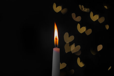 burning candle on a dark background with light from the lights, close-upの写真素材