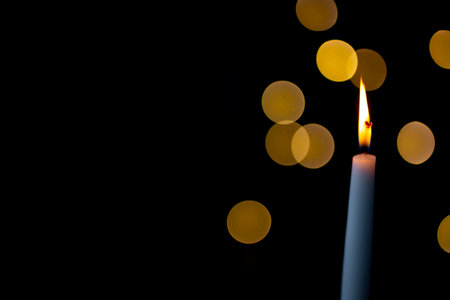 burning candle on a dark background with light from the lights, close-up