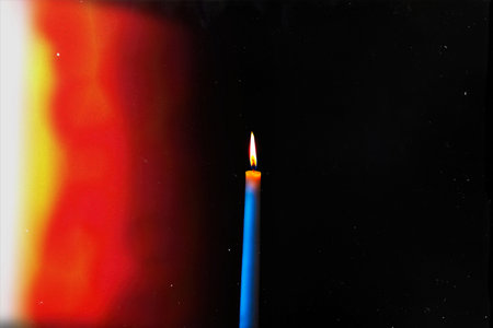 burning candle on a dark background with light from the lights, close-upの写真素材