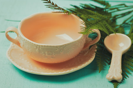 pink teacup with spoon and saucer on a wooden turquoise background top view, close-upの写真素材
