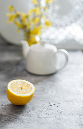 Half of fresh lemon and white teapot are on gray backgroundの写真素材